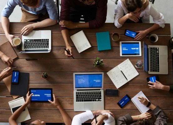 Photo from above showing people working with laptops and tablets on a wooden table